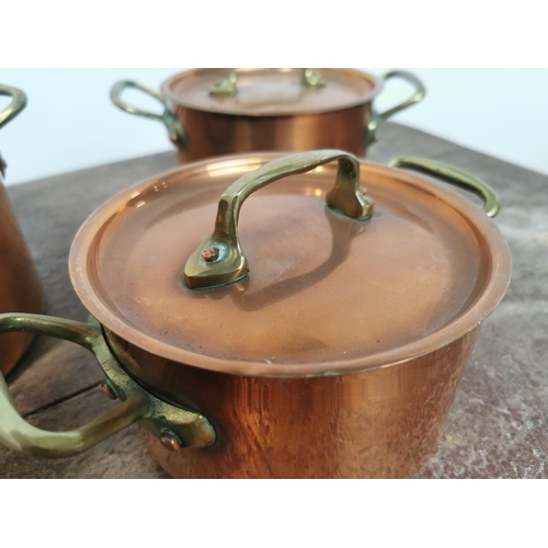 113 - A set of three copper and brass lidded saucepans {14cm H x 26cm W x 18cm D Largest /     10cm H x  2... 