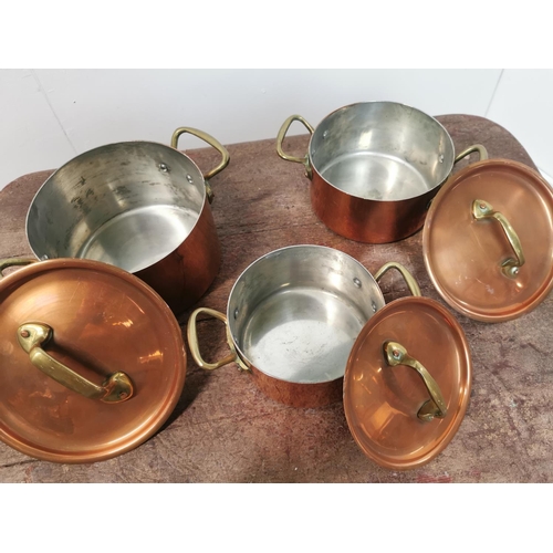 113 - A set of three copper and brass lidded saucepans {14cm H x 26cm W x 18cm D Largest /     10cm H x  2... 