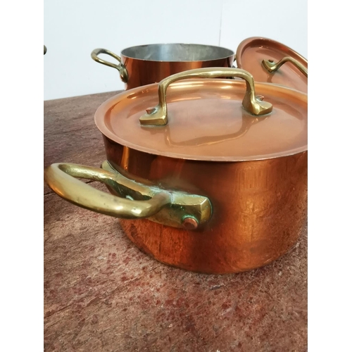 113 - A set of three copper and brass lidded saucepans {14cm H x 26cm W x 18cm D Largest /     10cm H x  2... 