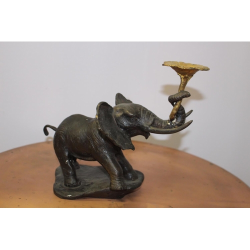 591 - Bronze model of an elephant holding a lotus flower { 23cm H X 32cm W X 12cm D }.