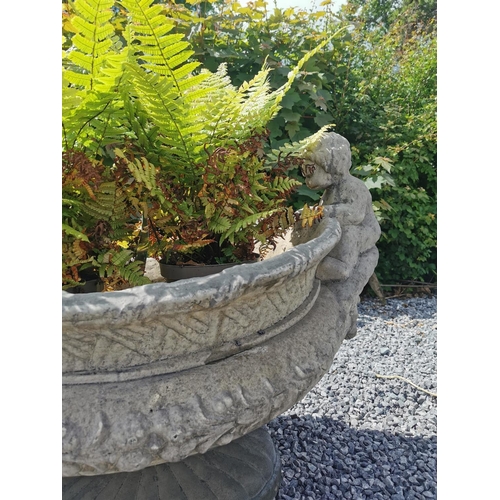 654 - Oval moulded stone urn decorated with cherubs seated above lion's masks. {70 cm H x 90 cm W x 55 cm ... 