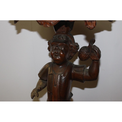 673 - Carved mahogany jardiniere stand, the column in the form of a boy holding fruit raised on three outs... 