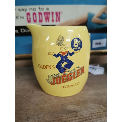 155 - Ogden's Juggler Tobacco advertising jug. 8 pence per ounce. {11 cm H x 10 cm W x 9 cm D}.