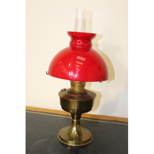 21 - Brass oil lamp with red glass shade {55 cm H x 24 cm Dia.}.