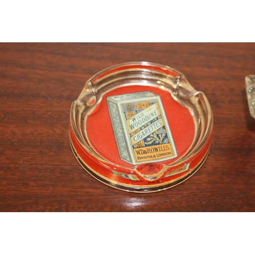 142 - Two Woodbine Cigarettes glass advertising ashtrays. {2 cm H x 10 cm Diam} and {4 cm H x 17 cm W x 13... 