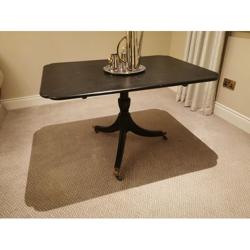 139 - Ebonised centre table with single column raised on three legs and brass feet in the Regency manner {... 