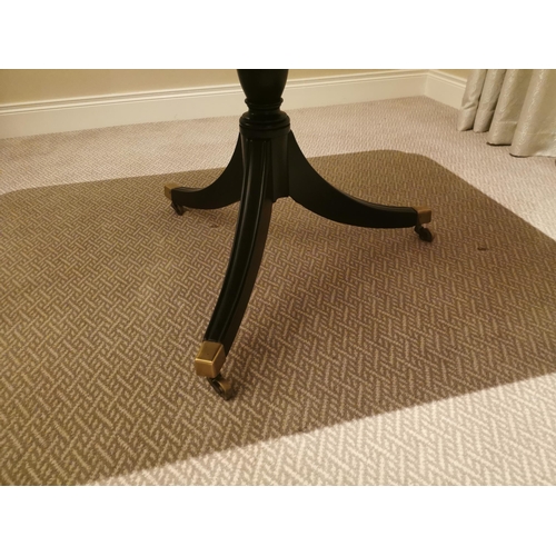 139 - Ebonised centre table with single column raised on three legs and brass feet in the Regency manner {... 
