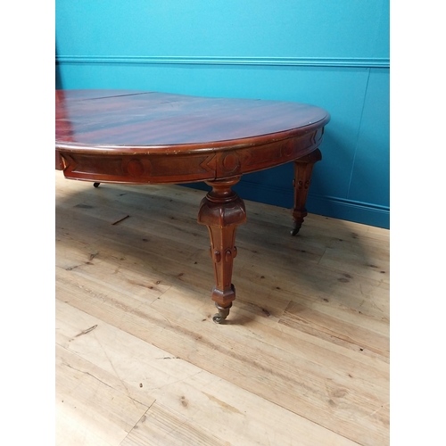 349 - 19th C. mahogany extendable dining table raised on fluted legs and brass castors with five leaves {8... 