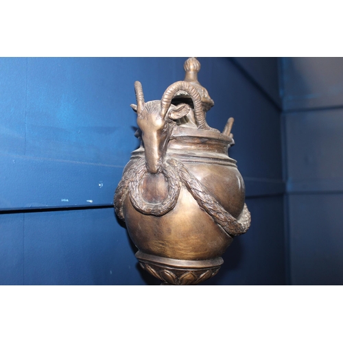 386 - Bronze lidded urn decorated with rams head  {H 45cm x W 20cm x D 18cm}.