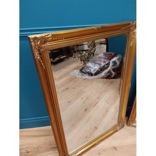 85 - Pair of decorative gilt wall mirrors with bevelled glass {104 cm H x 73 cm W}.