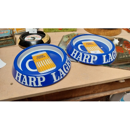 93 - Two tin plate Harp Lager advertising ashtrays. {3 cm H x 20 cm Dia.}.