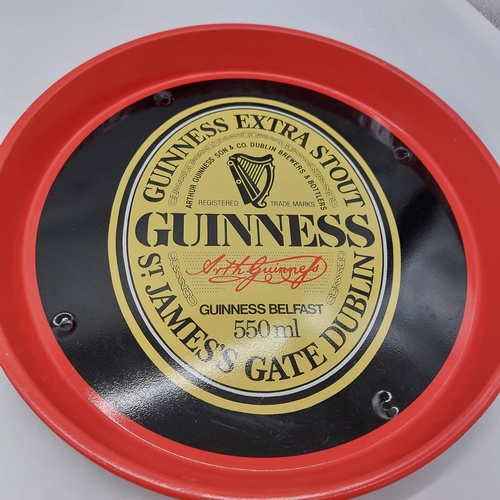 1263 - Two tinplate advertising trays  - Kaliber { some damage } & Guinness Extra Stout. Each 30cm Dia }.