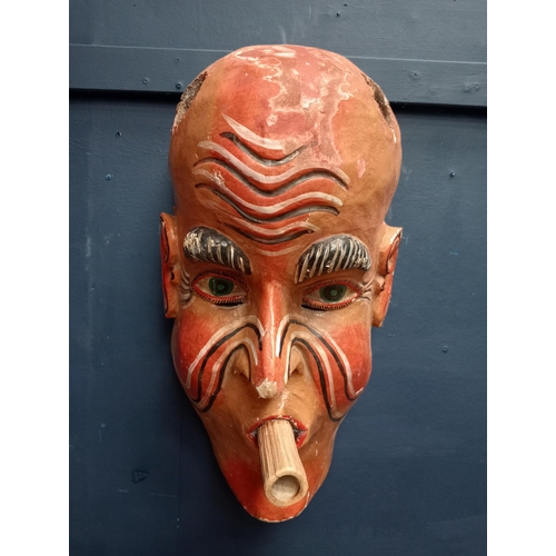 213 - Hand carved wooden mask with blowpipe  {H 53cm x W 27cm x D 15cm }.