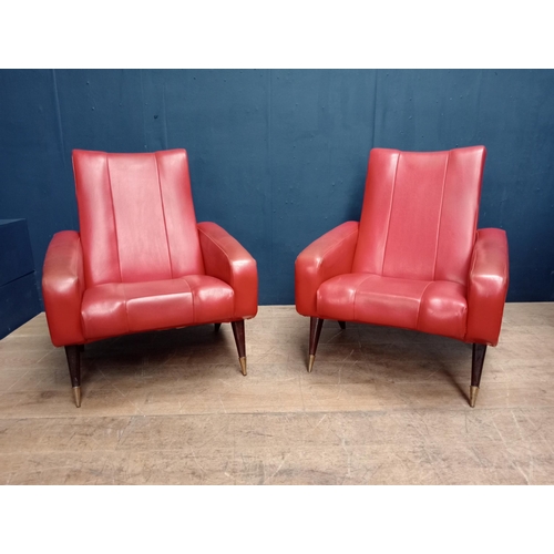 343 - Pair of Retro red leather armchairs raised on mahogany and brass legs.