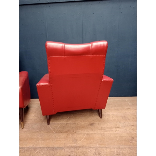 343 - Pair of Retro red leather armchairs raised on mahogany and brass legs.