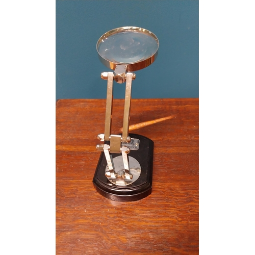 36 - Chrome and ebonised table magnifying glass {18 cm H x 18 cm W x 9 cm D}.