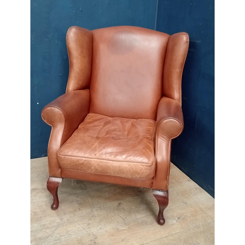 393 - Leather wingback arm chair raised on Queen Ann legs {H 105cm x W 78cm x D 75cm }.