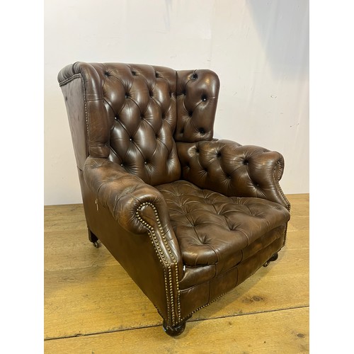 139 - Brown leather deep buttoned Chesterfield wingback armchair raised on brass castors  {H 96cm x W 94cm... 