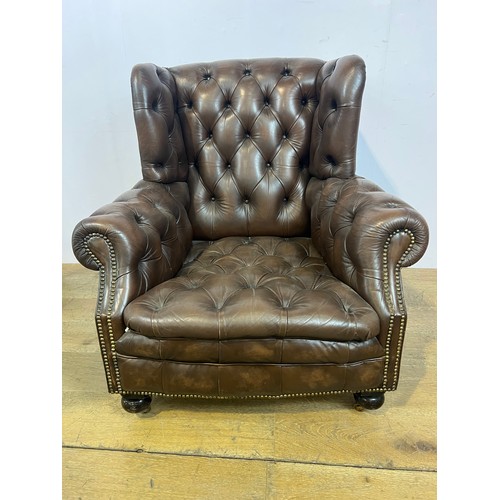 139 - Brown leather deep buttoned Chesterfield wingback armchair raised on brass castors  {H 96cm x W 94cm... 