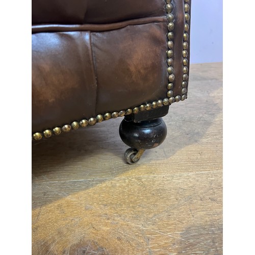 139 - Brown leather deep buttoned Chesterfield wingback armchair raised on brass castors  {H 96cm x W 94cm... 