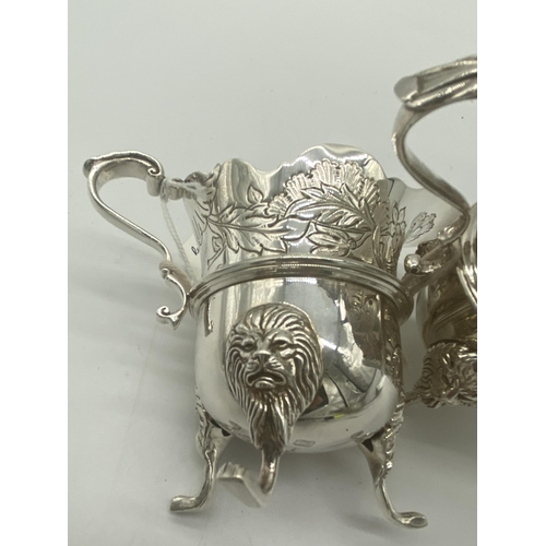 1354 - Pair of Irish silver milk jugs with hand chased florals to the top rim with an open monogram cartouc... 