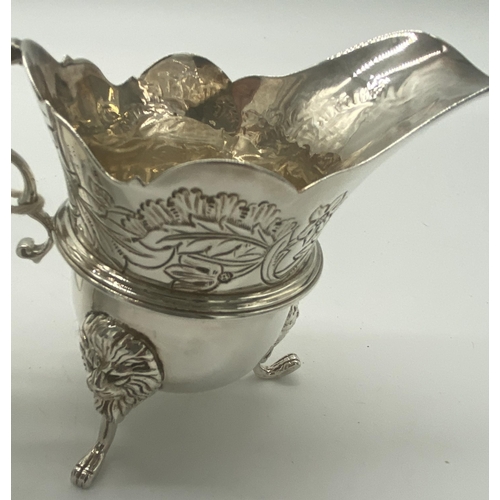 1354 - Pair of Irish silver milk jugs with hand chased florals to the top rim with an open monogram cartouc... 