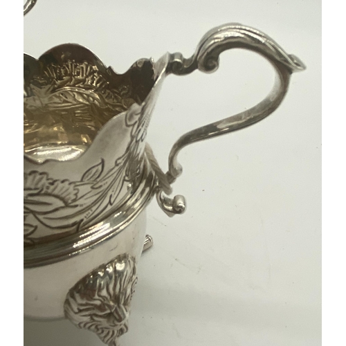 1354 - Pair of Irish silver milk jugs with hand chased florals to the top rim with an open monogram cartouc... 