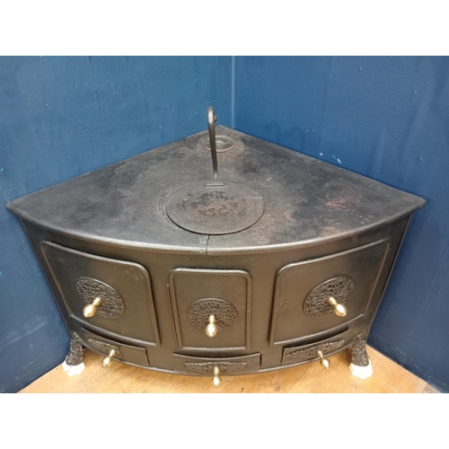 169 - Cast iron corner stove with brass knobs and aluminium feet {H 77cm x W 130cm x D 86cm }.