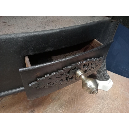 169 - Cast iron corner stove with brass knobs and aluminium feet {H 77cm x W 130cm x D 86cm }.