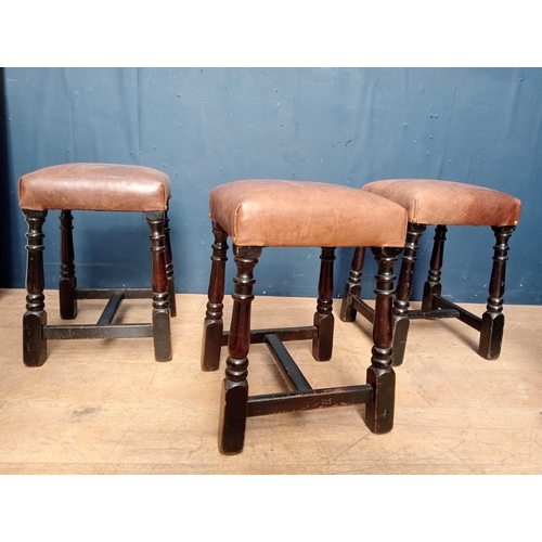 645 - Three brown leather low stools {H 47cm x W 36cm x D 36cm }.