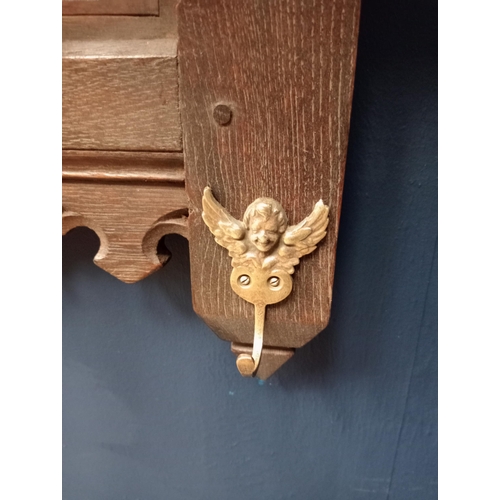 398 - Ornate carved oak coat rack with cherub brass hooks. {H 45cm x W 94cm x D 20cm }.