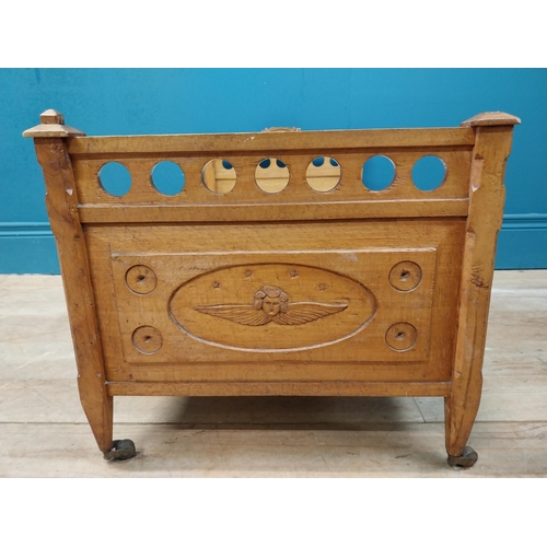 126 - Early 20th C. oak dog bed with side panels decorated with cherubs on tapered feet and brass casters.... 