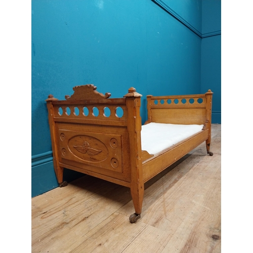 126 - Early 20th C. oak dog bed with side panels decorated with cherubs on tapered feet and brass casters.... 