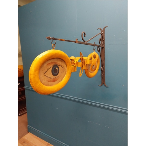 13 - Painted metal hanging Optician's sign with bracket. {69 cm H x 97 cm W x 17 cm D}.