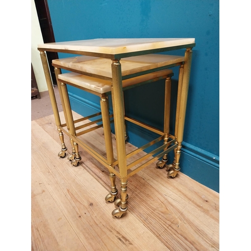 313 - Nest of three brass and onyx tables on casters. {54 cm H x 50 cm W x 32 cm D}.