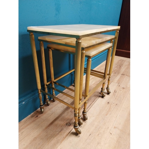 313 - Nest of three brass and onyx tables on casters. {54 cm H x 50 cm W x 32 cm D}.