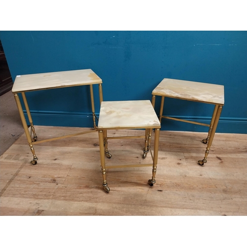 313 - Nest of three brass and onyx tables on casters. {54 cm H x 50 cm W x 32 cm D}.