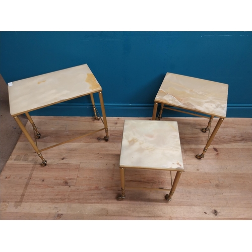 313 - Nest of three brass and onyx tables on casters. {54 cm H x 50 cm W x 32 cm D}.