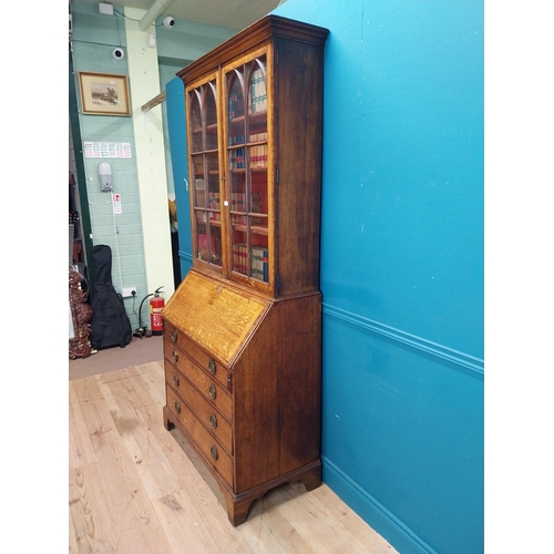 397 - Georgian oak bureau bookcase with fitted red velvet interior on bracket feet above two glazed doors.... 