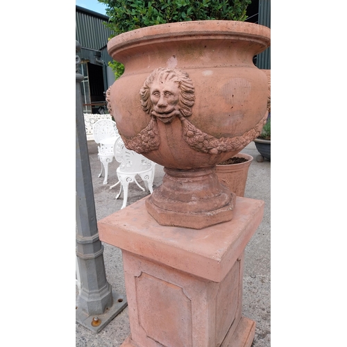 708 - Pair of good quality moulded terracotta urns decorated with lions masks and swags raised on pedestal... 