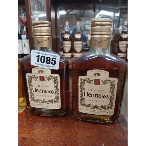 1085 - Four vintage naggins of Hennessy Brandy and one John Powers.