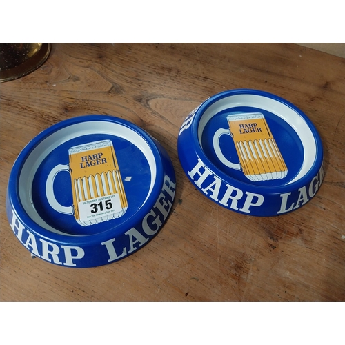 315 - Two tin plate Harp Lager advertising ashtrays. {3 cm H x 20 cm Dia.}.