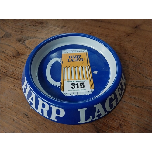 315 - Two tin plate Harp Lager advertising ashtrays. {3 cm H x 20 cm Dia.}.