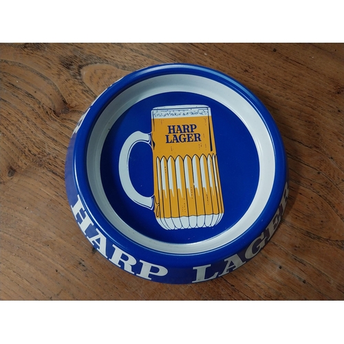 315 - Two tin plate Harp Lager advertising ashtrays. {3 cm H x 20 cm Dia.}.