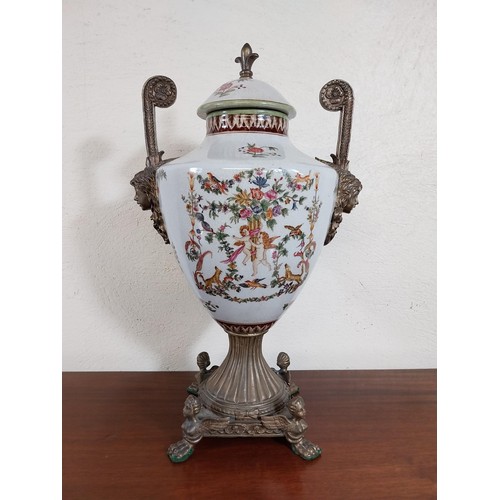 112 - Decorative ceramic and gilded metal lidded urn decorated with cherubs and floral gardlands.  {45 cm ... 