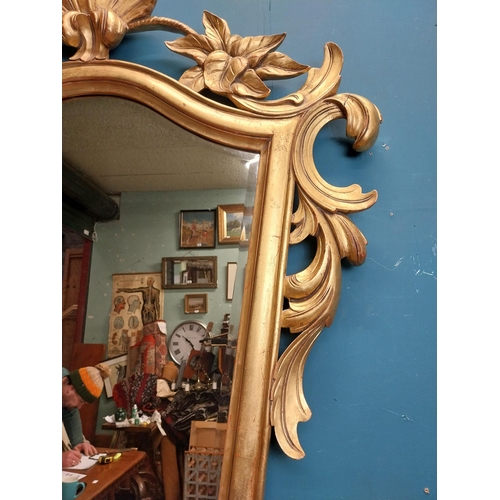 964 - Gilt wall mirror mounted in a shield shaped frame surmounted with foliage. { 157cm H X 110cm W }.