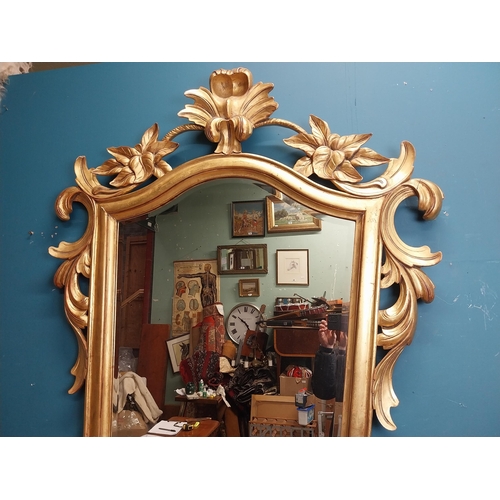 964 - Gilt wall mirror mounted in a shield shaped frame surmounted with foliage. { 157cm H X 110cm W }.