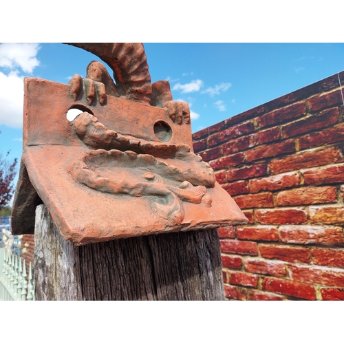 599 - Pair of moulded terracotta ridge tiles surmounted with Dragons {}.