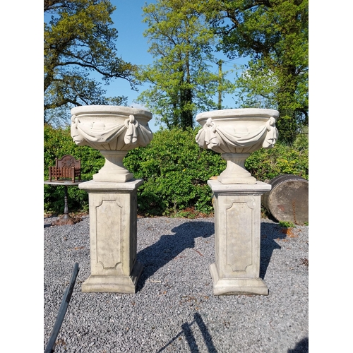 948 - Pair of moulded sandstone urns decorated with swag raised on pedestals {152 cm H x 67 cm Dia.}.