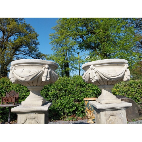 948 - Pair of moulded sandstone urns decorated with swag raised on pedestals {152 cm H x 67 cm Dia.}.